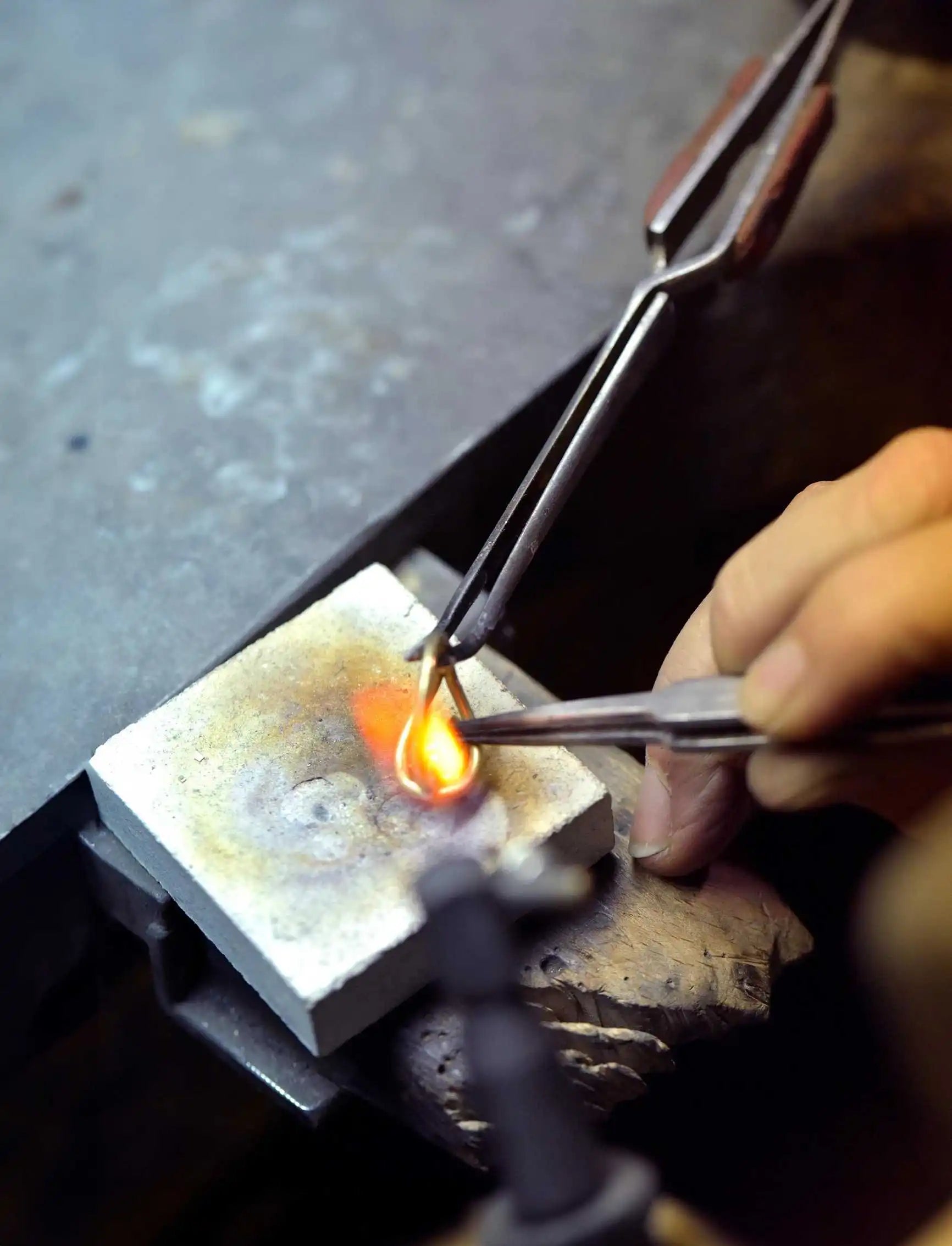A jeweller crafting a ring in the Okker & Ockers atelier, using precision tools to solder the metal under intense heat.