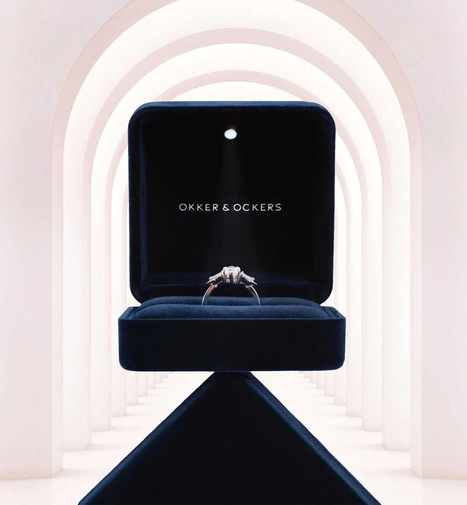 An Okker & Ockers ring presented in the branded velvet jewellery box and illuminated by a light.