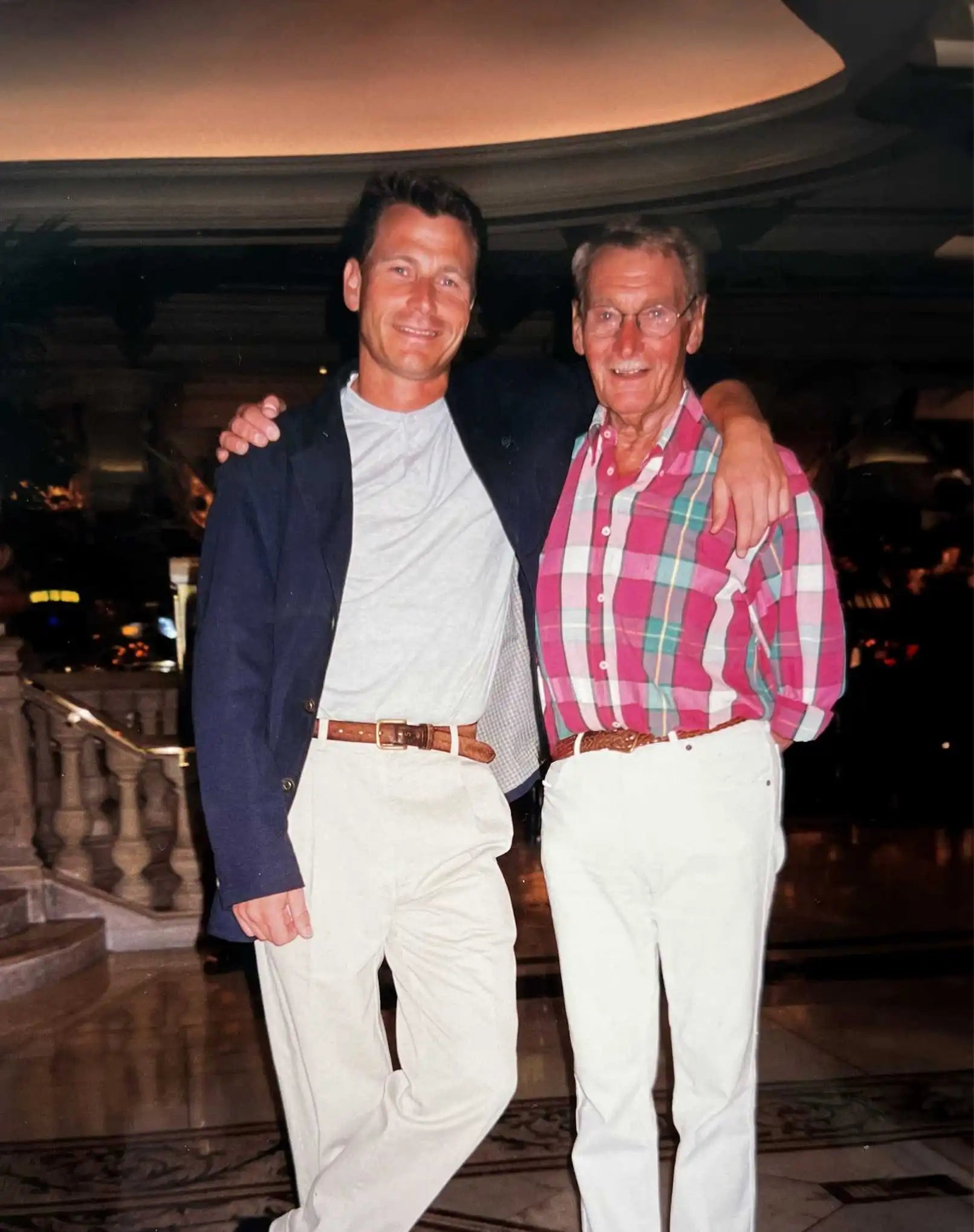 Antony Okker with his father, Nico Okker, standing together in an elegant setting, dressed in smart casual attire.