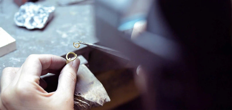 A jeweller carefully assembling the Floating Pear Icon ring in the atelier, using precision tools to craft the gold setting.